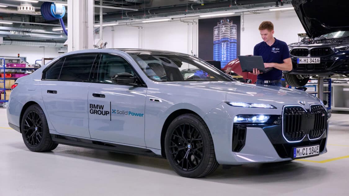 An engineer works on a laptop connected to a BMW i7 test vehicle with Solid Power all-solid-state battery technology inside a BMW Group workshop.