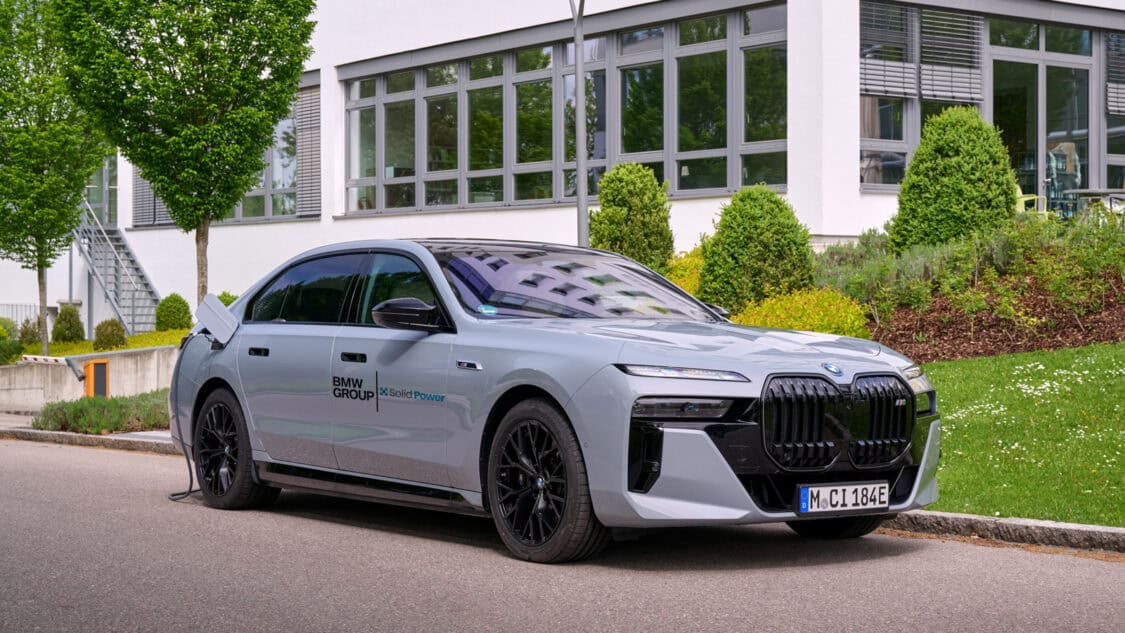 A BMW i7 test vehicle with Solid Power all-solid-state battery technology is shown charging outside a BMW Group facility.