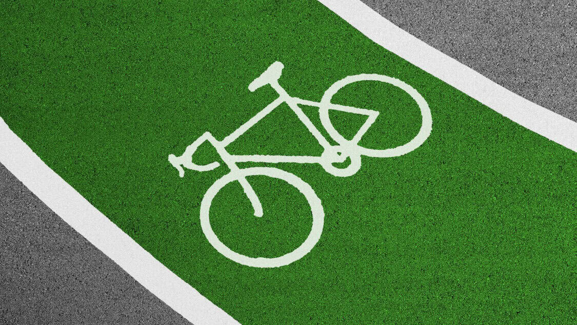 Green bike lane with a white bicycle symbol painted on it.