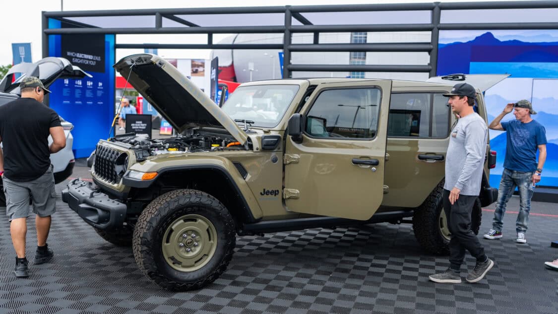 A Jeep Wrangler 4xe with its hood open is showcased in the Stellantis booth at Electrify Expo Phoenix.