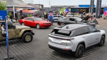 A variety of Dodge and Jeep electric vehicles, including a red Dodge Charger, black Dodge Charger Daytona, silver Wagoneer S, and tan Jeep Wrangler 4xe, are showcased in the Stellantis booth at Electrify Expo Phoenix.
