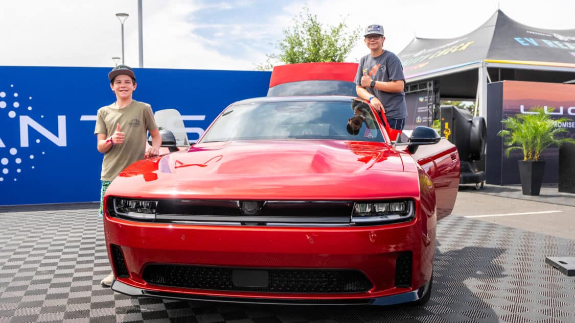 A red Dodge Charger EV electric muscle car is displayed outdoors at the Stellantis booth at Electrify Expo Phoenix.