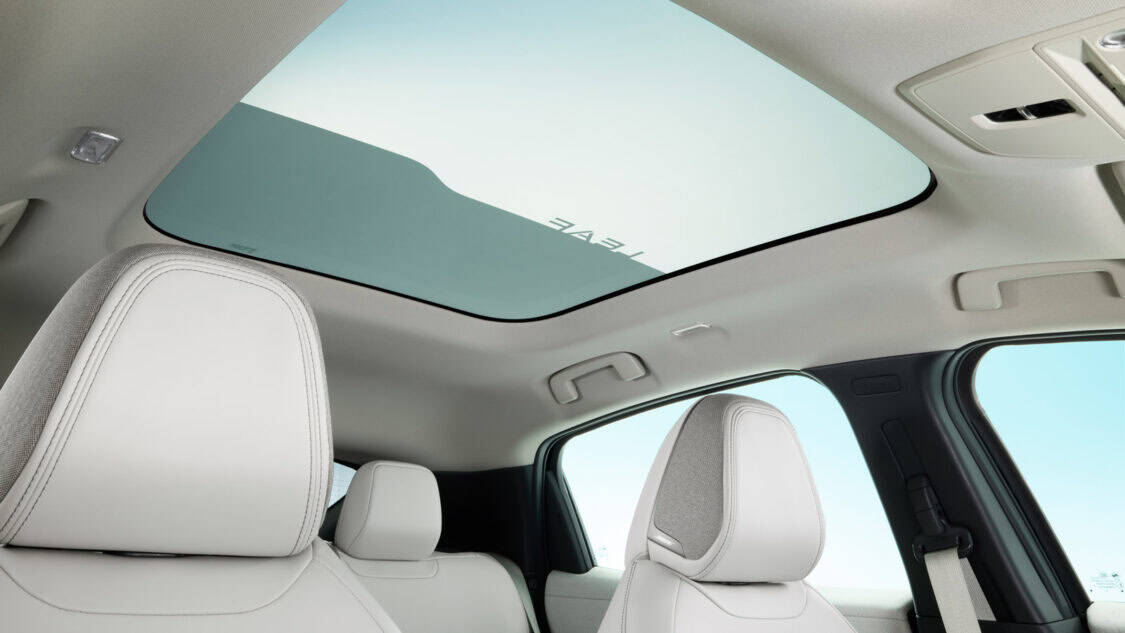 Interior view of the 2026 Nissan Leaf featuring the dimming panoramic roof, light gray headliner, and white seats with integrated Bose speakers.