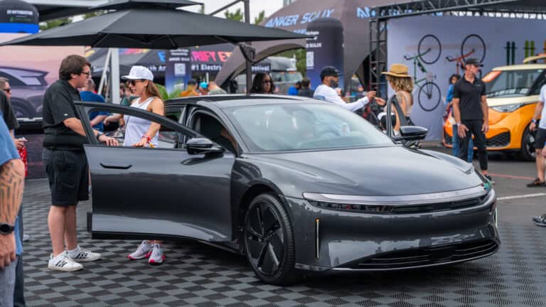 Lucid Air electric sedan with doors open at Electrify Expo Phoenix, as attendees interact with the vehicle and staff