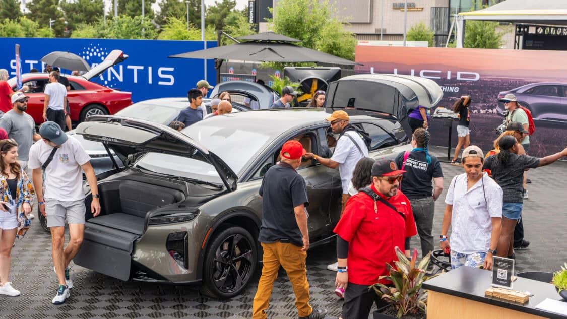 Crowds gather around the Lucid Gravity SUV at Electrify Expo Phoenix, featuring its open front trunk with integrated bench seating on display