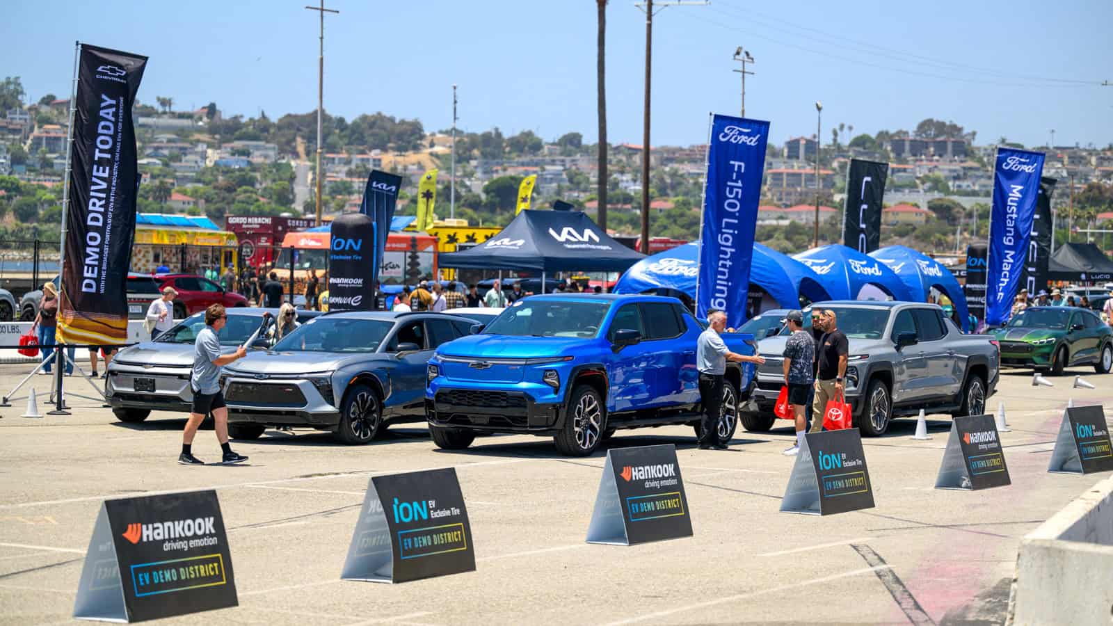 EV Demo District at Electrify Expo, featuring Chevrolet Silverado EV, Chevrolet Blazer EV, and Ford Mustang Mach-e.
