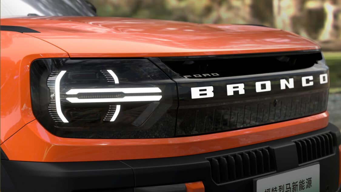 Close-up of the electric Ford Bronco New Energy’s front grille and headlights, featuring the Badlands badge and signature flush door handle