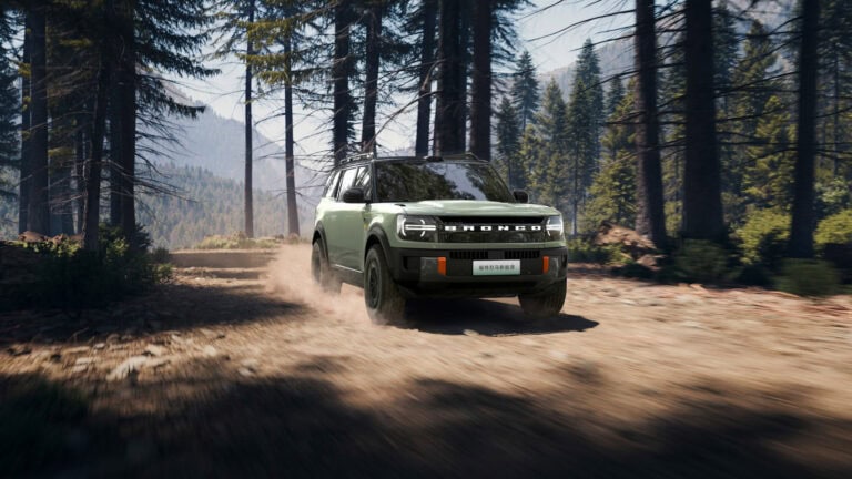 Ford Bronco New Energy electric SUV kicking up dust on a forest trail in China, highlighting its off-road stance and EV design.