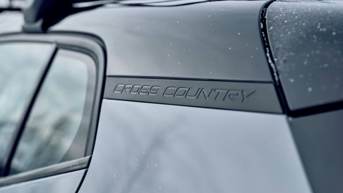 Close-up of the “Cross Country” badging on the 2026 Volvo EX30 Cross Country, displayed on the rear pillar with matte black trim and light snow accumulation.