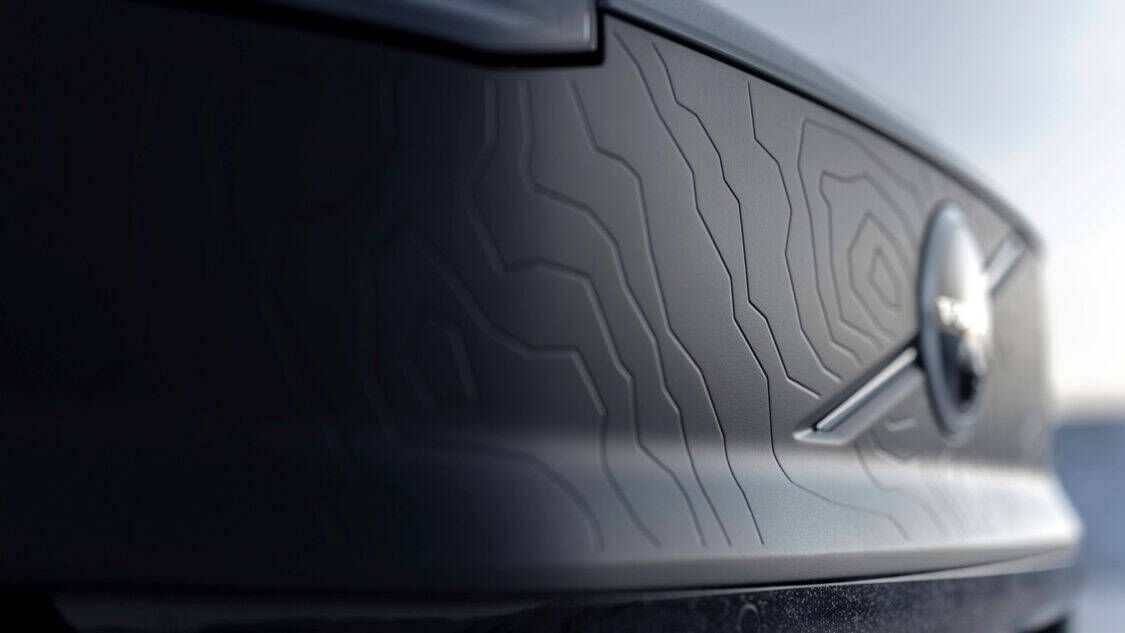 Close-up of the front matte black shield on the 2026 Volvo EX30 Cross Country, featuring an embossed topographic map design and Volvo emblem.