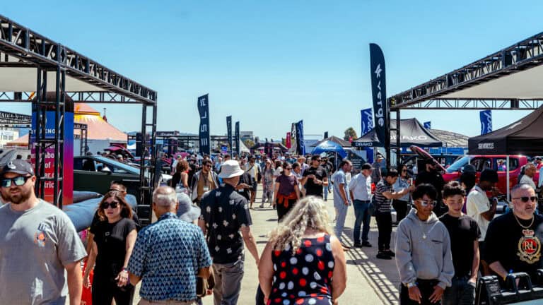 Crowds walk through Electrify Expo San Francisco lined with banners and dealer booths, highlighting the rush to secure federal tax credits before deadlines.