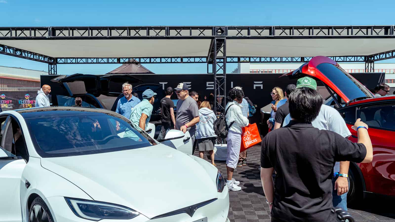 Visitors gather at a Tesla display during Electrify Expo, exploring EVs as buyers rush to secure federal tax credits before deadlines.