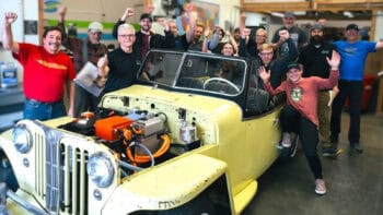 Group of Fuel2Electric and Switch Vehicles trainees celebrating around a classic car converted to electric during hands-on EV training.