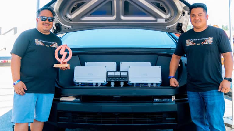Jason Digos of Modus and his son Jaren Digos of Delta Concepts stand beside the award-winning Modus Tesla Cybertruck audio build at Electrify Showoff, with Jason holding a trophy.