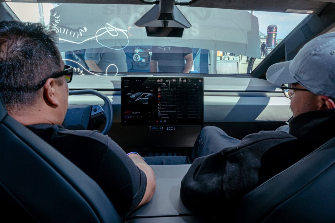 Two attendees sit inside the TELO MT1 electric mini truck at Electrify Expo San Francisco, checking out its minimalist dashboard and large center screen.