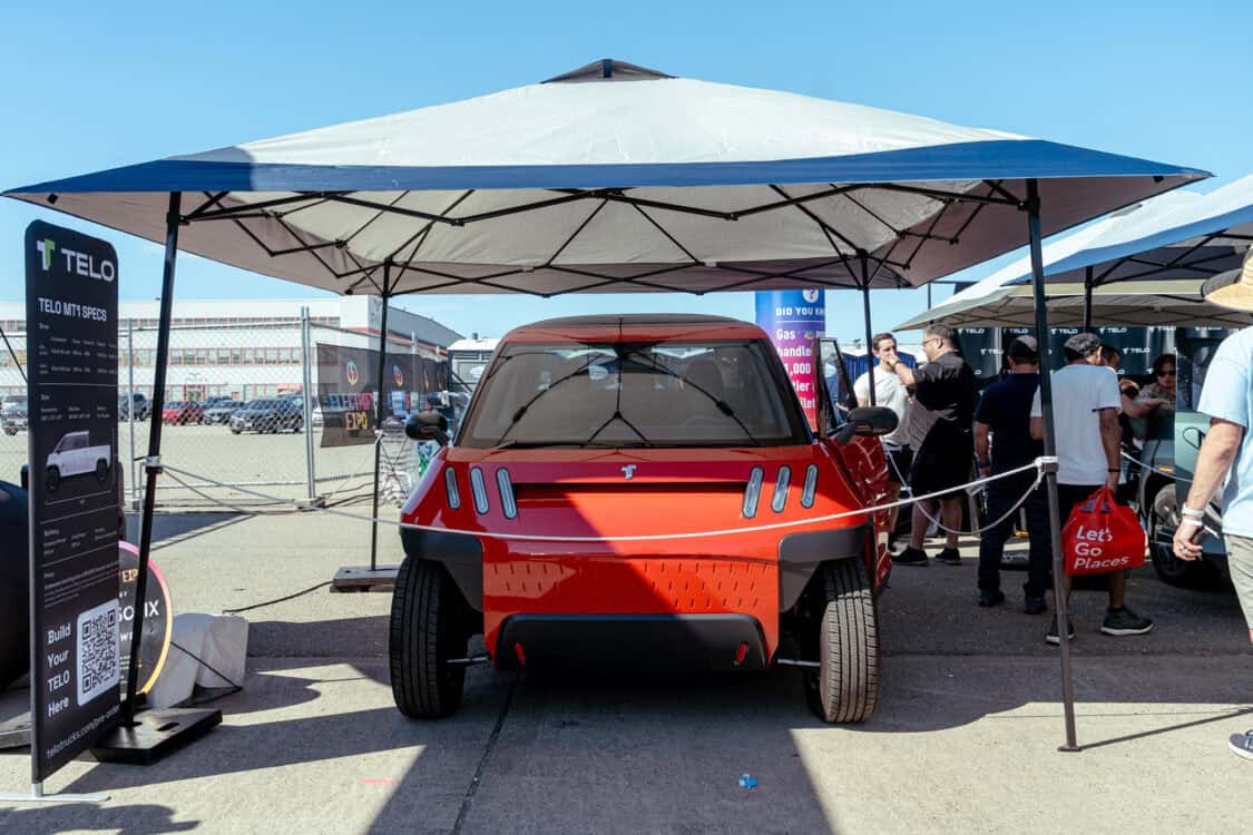 The red TELO MT1 electric mini truck on display under a canopy at Electrify Expo San Francisco, with a spec board nearby.