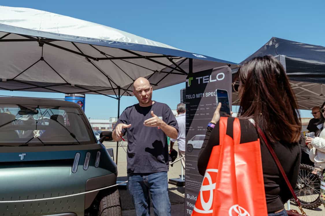 An attendee discusses MT1 specs for a video at Electrify Expo San Francisco, next to the electric mini truck display.
