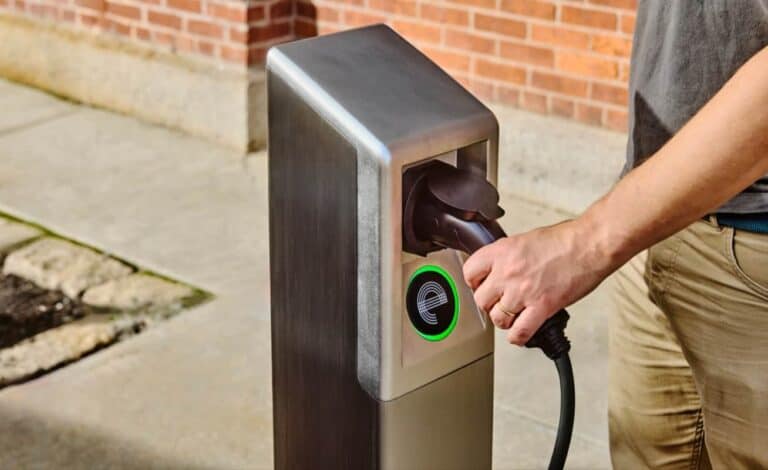 A person plugs into an It’s Electric curbside charging station in Alameda, part of the city’s clean energy expansion for renters.