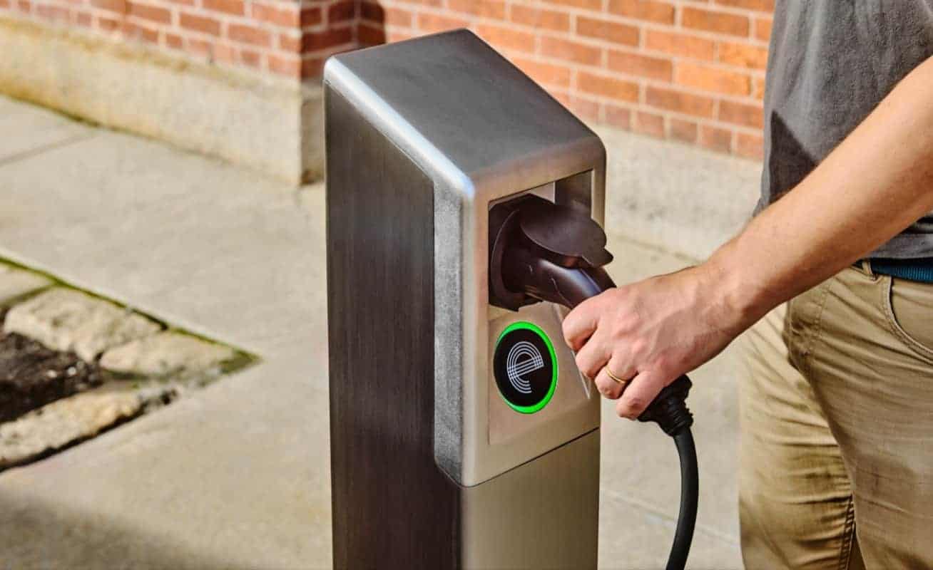 A person plugs into an It’s Electric curbside charging station in Alameda, part of the city’s clean energy expansion for renters.
