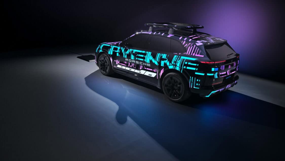 Porsche Cayenne Electric prototype aligned over a wireless charging pad glowing under purple and blue lighting.