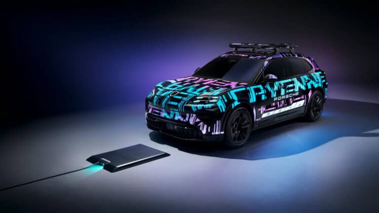 Porsche Cayenne Electric prototype aligned over a wireless charging pad glowing under purple and blue lighting.