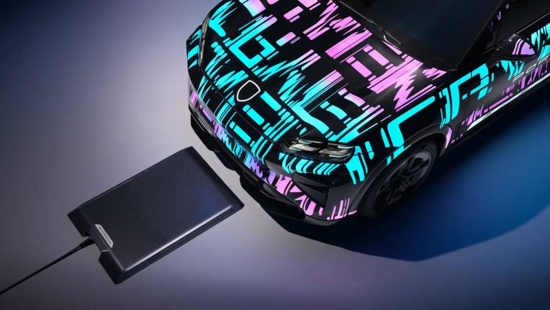 Porsche Cayenne Electric prototype aligned over a wireless charging pad glowing under purple and blue lighting.
