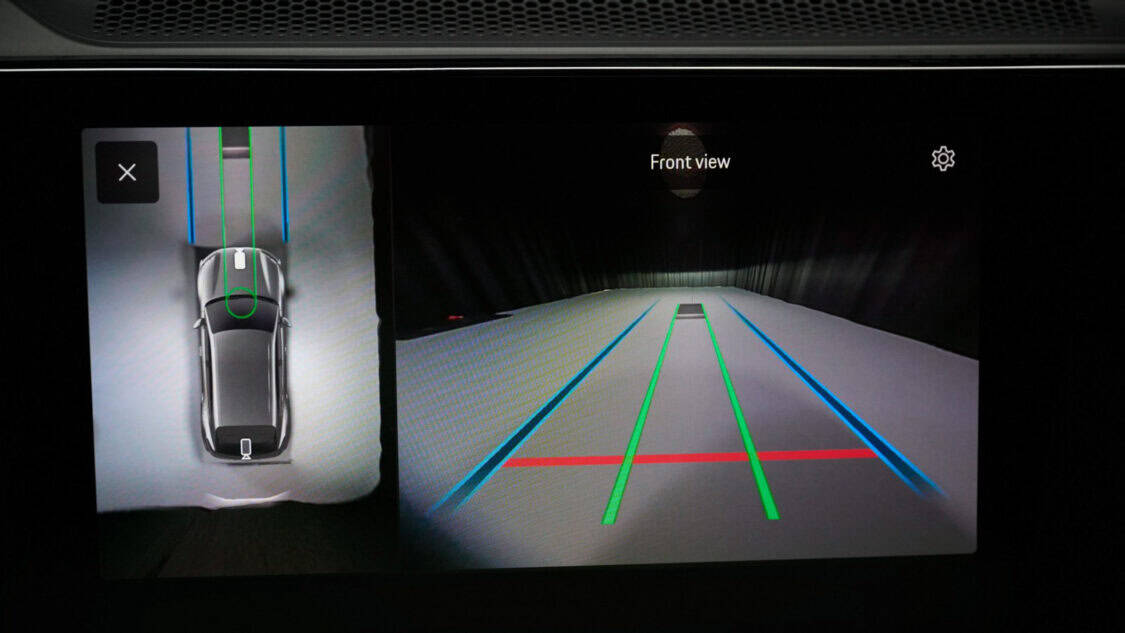 Porsche Cayenne Electric prototype aligned over a wireless charging pad glowing under purple and blue lighting.