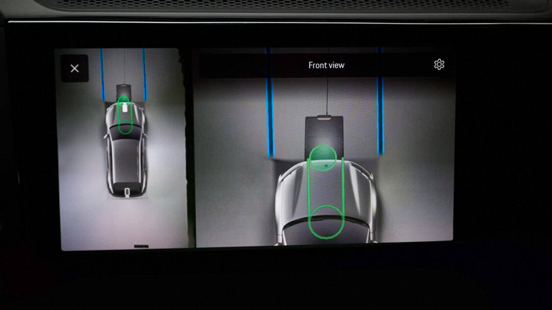 Porsche Cayenne Electric prototype aligned over a wireless charging pad glowing under purple and blue lighting.