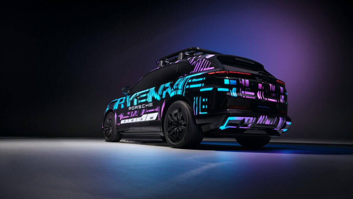 Porsche Cayenne Electric prototype aligned over a wireless charging pad glowing under purple and blue lighting.
