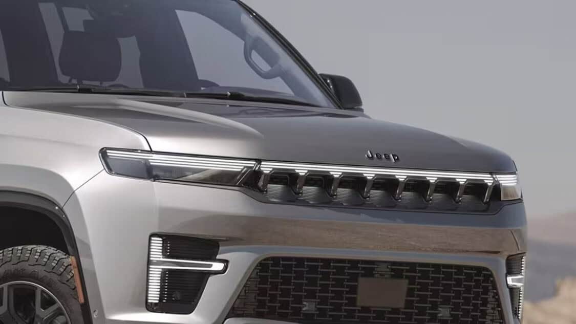 Front view of the 2026 Jeep Grand Wagoneer showing its illuminated grille and modern LED headlights.