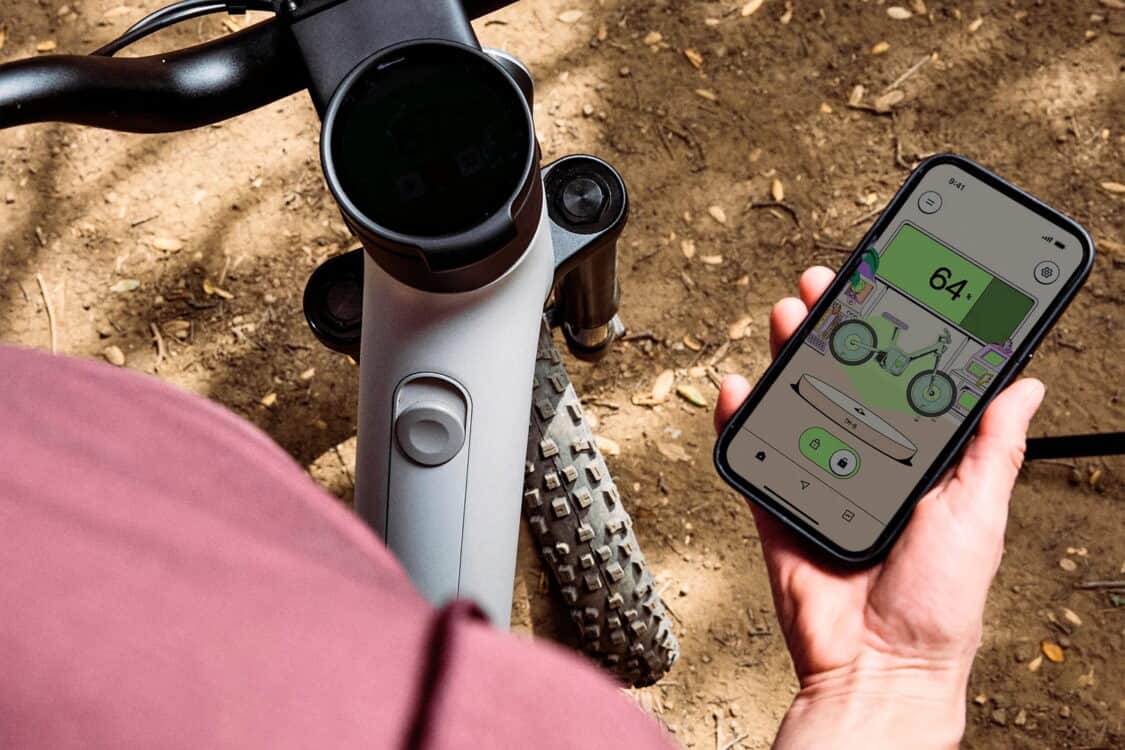 Rider using the ALSO TM-B e-bike companion app to check battery status and ride data.
