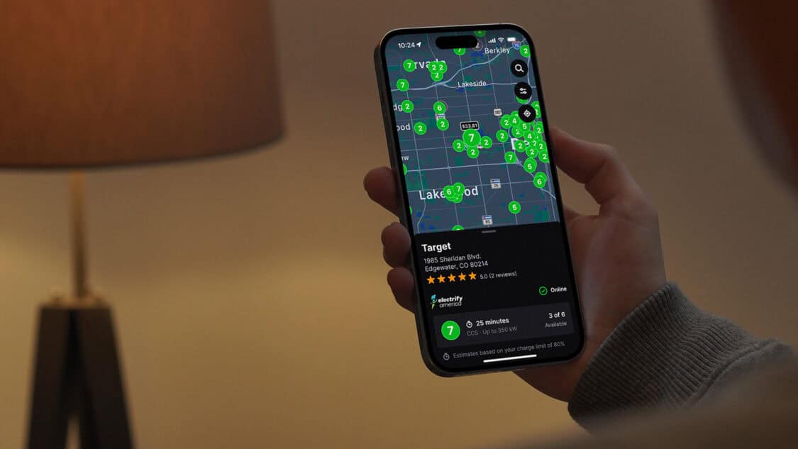 A person holding a smartphone displaying the Chargeway app with real-time EV charging prices and station locations near Lakewood, Colorado.