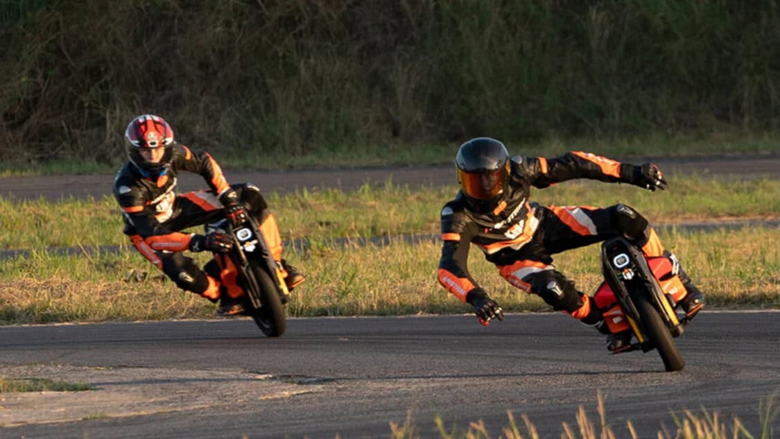 Two riders in racing suits corner sharply on InMotion P6 electric unicycles, testing high-speed performance and precision handling on track.