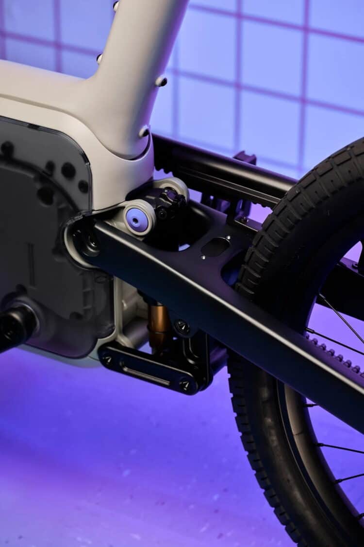 Close-up of the ALSO TM-B e-bike rear suspension and motor housing under purple lighting.