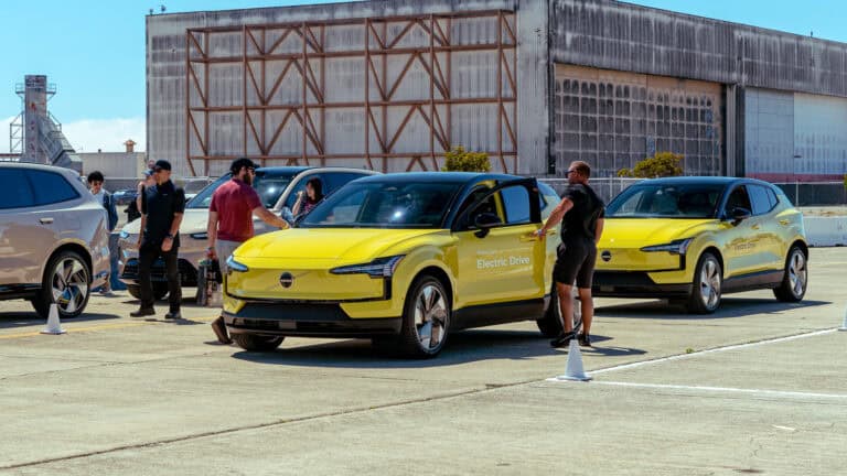 Attendees check out two yellow Volvo EX30 electric SUVs during a demo and test drive session at Electrify Expo, with staff guiding participants on the course.