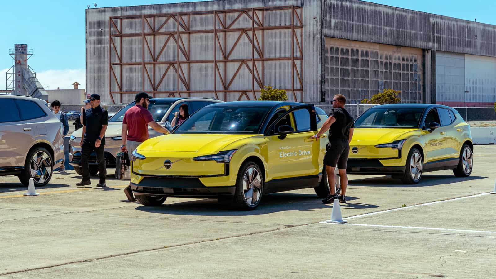 Attendees check out two yellow Volvo EX30 electric SUVs during a demo and test drive session at Electrify Expo, with staff guiding participants on the course.