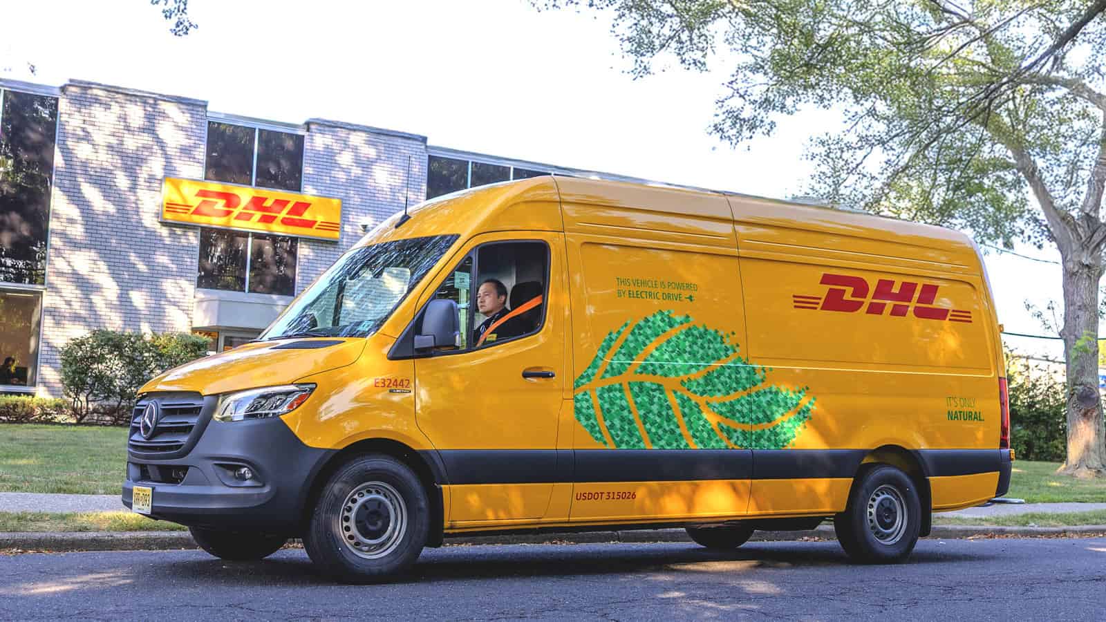 A yellow DHL Mercedes-Benz eSprinter electric van parked outside a DHL facility, highlighting its zero-emission delivery message and green leaf graphic.