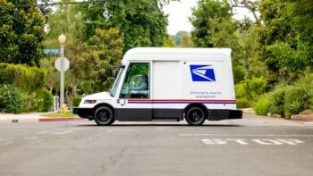 USPS electric mail truck driving through a neighborhood, highlighting the shift to cleaner holiday deliveries.