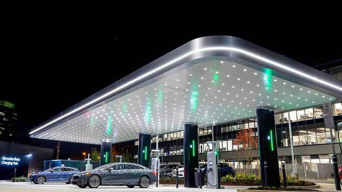 Mercedes-Benz EV fast power hub at a retail destination, featuring multiple high-speed stalls under a covered canopy with vehicles parked during a shopping visit.