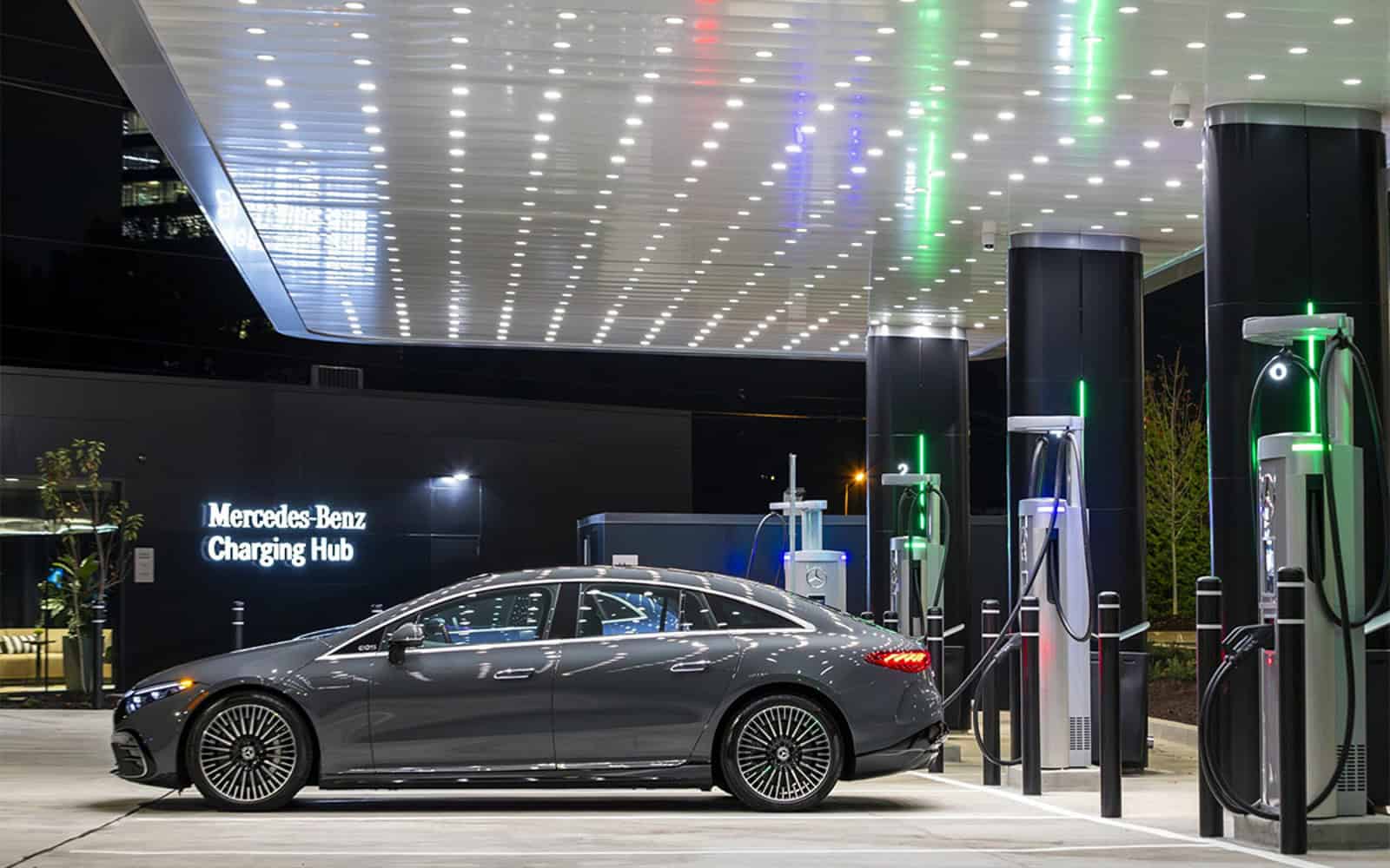 Mercedes-Benz high power EV hub with multiple power stalls under a covered canopy, featuring an electric sedan parked at a retail-style location during a short stop.