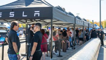 Attendees waiting in line for Tesla electric vehicle test drives at Electrify Expo under Tesla-branded tents